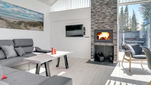 Een moderne woonkamer met een grijze bank, een witte tafel en een open haard.