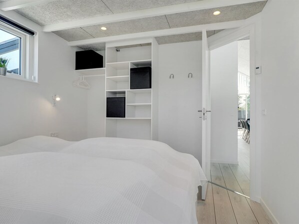 A modern bedroom with a large bed, built-in shelving, and a view of the outdoors.