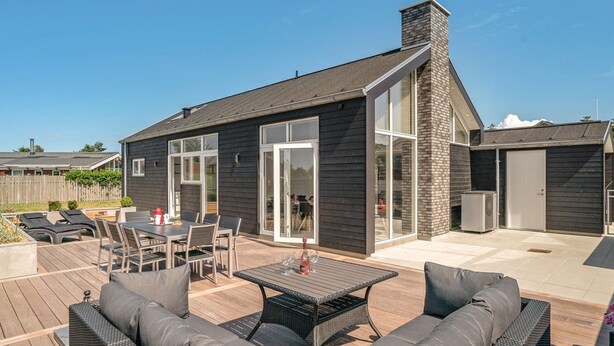Een modern huis met een patio, compleet met een eethoek en tuinmeubilair.