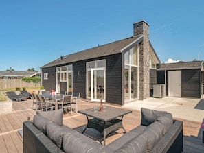 A modern house with a patio area featuring a dining set and outdoor furniture.