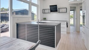 Een moderne keuken met grote ramen, een centraal eiland en uitzicht op de achtertuin.