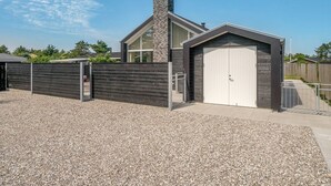 Een modern gebouw met garage, een hekpoort en een grindpad.