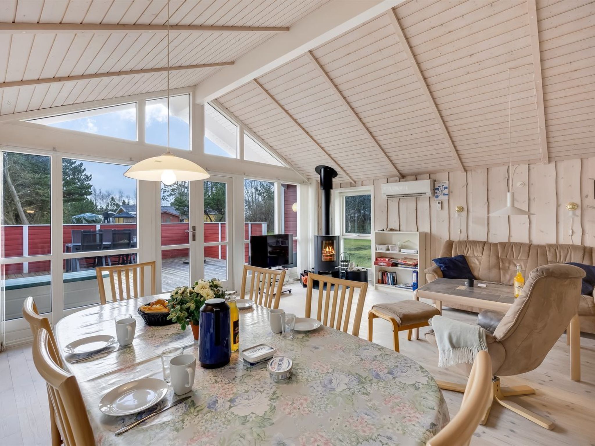 Amplia sala de estar con techo alto, ventanas grandes, chimenea y un rincón de estar acogedor.