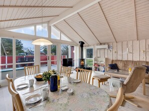 A spacious living area with a high ceiling, large windows, a fireplace, and a cozy seating area.