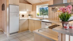 Eine moderne Küche mit Holzwänden, einem eingebauten Geschirrspüler und einem Fenster mit Blick auf Bäume.