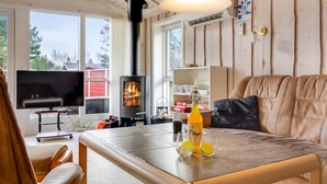 Ein gemütliches Wohnzimmer mit Kamin, Fernseher und einem Tisch mit Gläsern und einer Flasche.