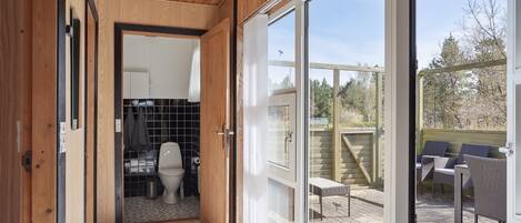 A narrow hallway leading to a bathroom with a toilet and a shower area.