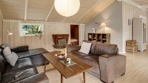 Ein gemütliches Wohnzimmer mit Ledersofas, einem Holztisch, einer Pendelleuchte und einem Bücherregal.
