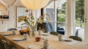 Ein Essbereich mit Holztisch, Stühlen, einer Blumenvase und einer großen Hängeleuchte.