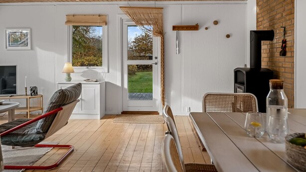 Una habitación acogedora con techo de madera, una mesa de comedor con sillas, un sofá, un televisor y una chimenea.