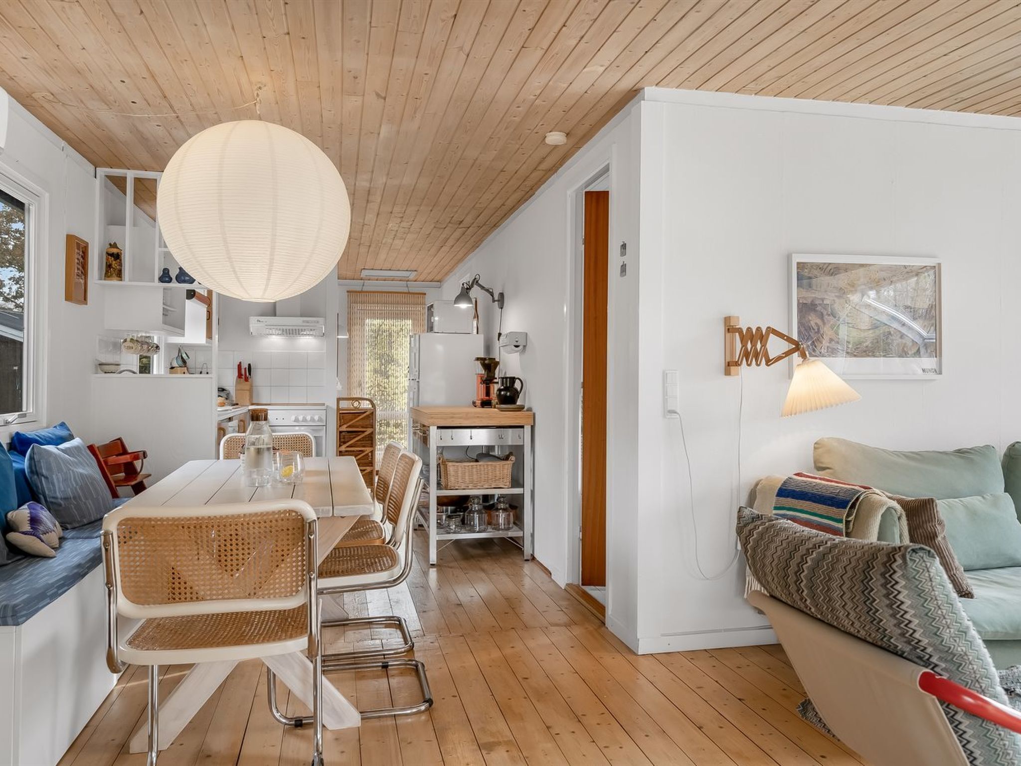 Een moderne woonkamer met een eethoek, houten vloeren en een plafond met zichtbare balken.