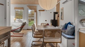 Un comedor moderno con techo de madera, una lámpara colgante grande y vistas al exterior.