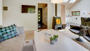 Un salon moderne avec un canapé blanc, un fauteuil en cuir noir, une table basse blanche et une cheminée.