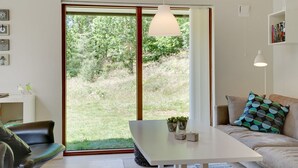 Un salon moderne avec une table blanche, un canapé agrémenté de coussins à motifs et une bibliothèque.