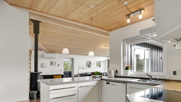Eine moderne Küche mit weißen Schränken, Holzböden und einem großen Fenster, das für natürliches Licht sorgt.