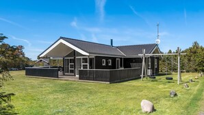 Ein modernes Gebäude mit überdachter Terrasse, Satellitenschüssel und Schaukel.