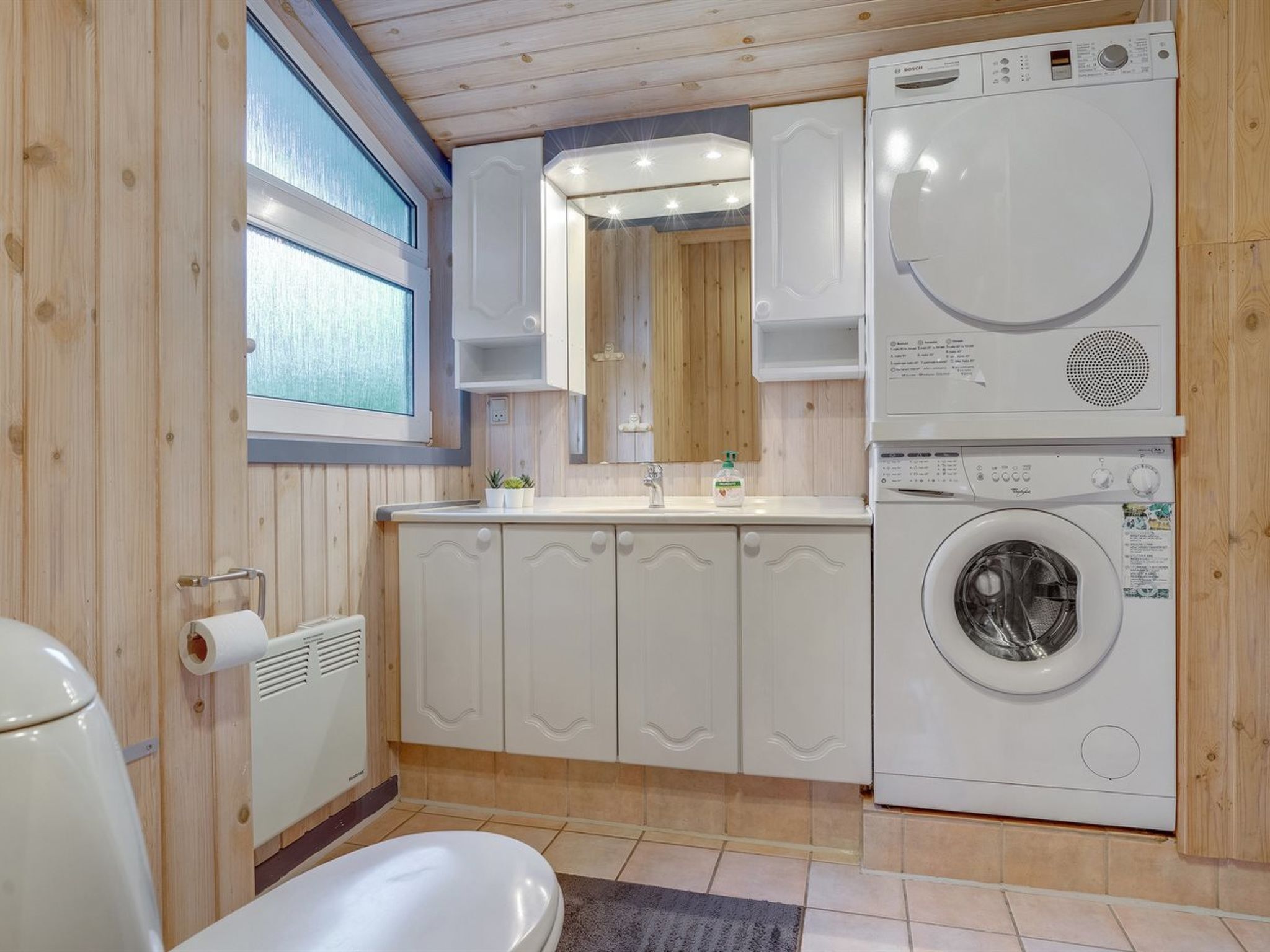 Une petite salle de bain comprenant des toilettes, un lavabo et un lave-linge.