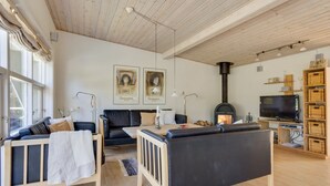 En hyggelig stue med pejs, sofa, lille bord og fjernsyn.