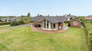 A modern house with a large deck, surrounded by a well-maintained lawn and neighboring houses. - "Kimi" - 800m from the sea by Interhome (Glesborg)
