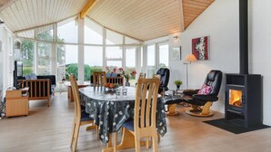 A spacious living area with a high ceiling, a fireplace, and large windows offering a view of the outdoors. - "Kimi" - 800m from the sea by Interhome (Glesborg)
