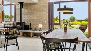 Una sala de estar moderna con chimenea, ventanas amplias y un comedor.