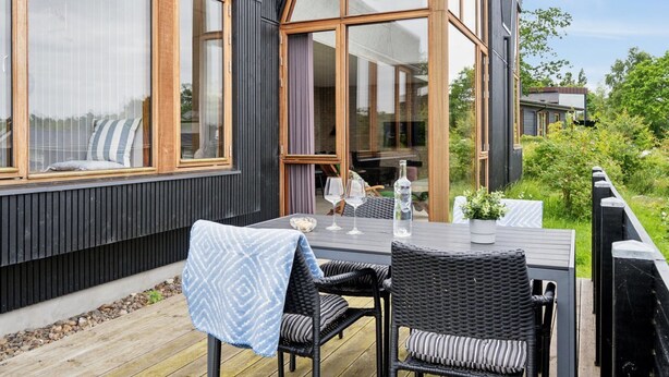 Un área de estar al aire libre moderna con una mesa, dos sillas de mimbre y un mantel estampado azul.