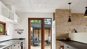 Una cocina moderna con una isla grande, una pared de acento de ladrillo y un ventanal corredero que da a un espacio exterior.