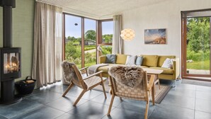 Een gezellige woonkamer met een open haard, een bank, twee fauteuils en een eettafel.