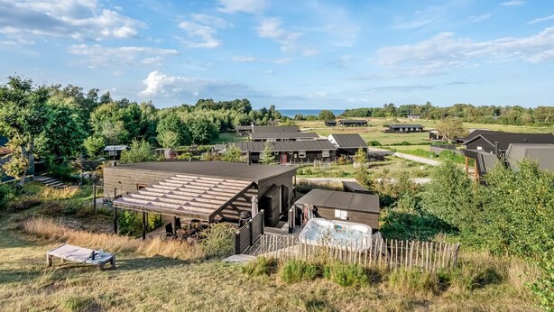 Een landelijke omgeving met meerdere vakantiehuisjes, een houten terras en een jacuzzi.