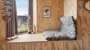 Een knus vertrek met houten inrichting, een groot raam en een stoel.