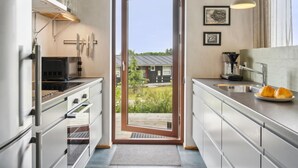 Een moderne keuken met roestvrijstalen apparatuur, een groot raam en uitzicht op de omgeving.