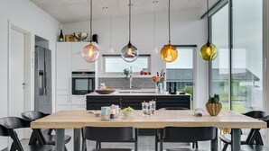 Une cuisine moderne dotée d’un îlot central, de chaises noires et de luminaires suspendus.