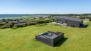 Une maison moderne dotée d’un grand jardin, d’un jacuzzi et offrant une vue sur la mer.