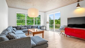 Una sala de estar moderna con un sofá seccional, una mesa de centro, un mueble de entretenimiento rojo y un televisor grande.