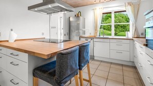 Una cocina moderna con encimera de madera, electrodomésticos de acero inoxidable y vistas al exterior.