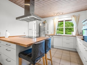 Una cocina moderna con encimera de madera, electrodomésticos de acero inoxidable y vistas al exterior.
