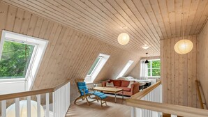 Un interior de madera con un dormitorio en entrepiso, una zona de comedor y una escalera.