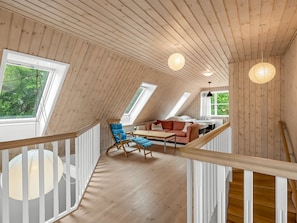 Et træbeklædt interiør med et sovehems, et spiseområde og en trappe.