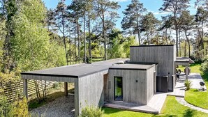 Ett modernt hus med en inglasad uteplats, en liten terrass och ett stort fönster.