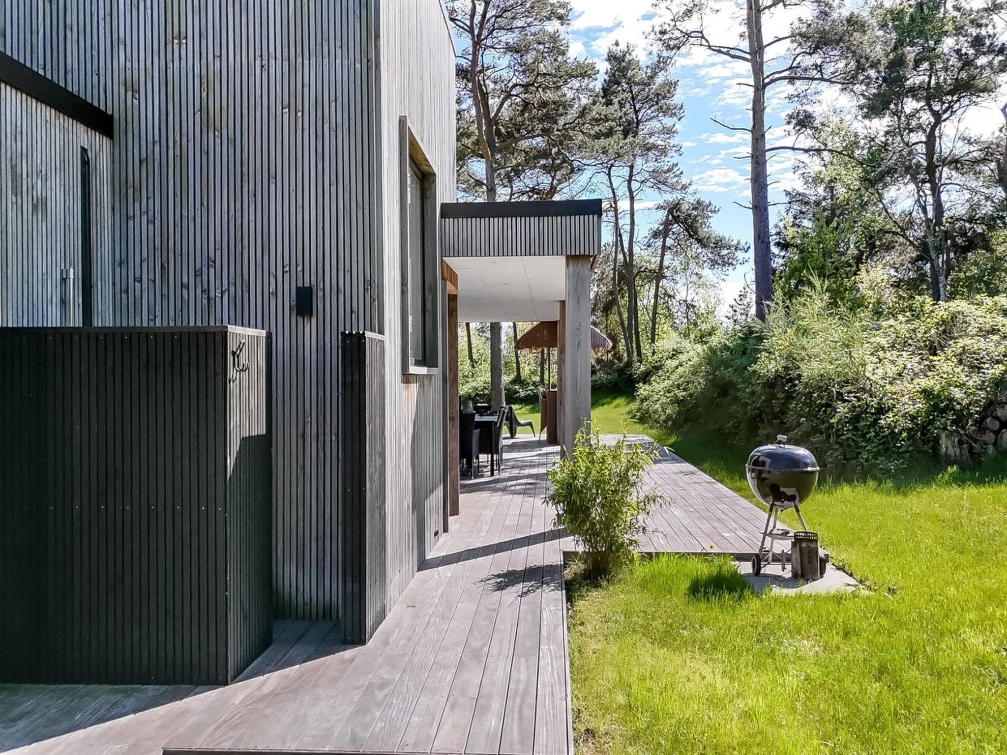 A modern house with a wooden deck and a covered outdoor seating area.
