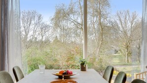 Een eettafel met stoelen, een broodkom, een fruitschaal en een glas water.