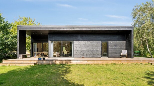 Een modern huis met een plat dak, grote glasramen en een houten terras.