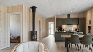 Een modern interieur met een centraal gelegen open haard, een eethoek en een keuken.