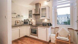 Une cuisine moderne avec des meubles blancs, un four à micro-ondes, un grille-pain et un plancher en bois.