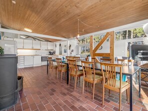 Une cuisine spacieuse avec des meubles blancs, un coin repas avec des chaises en bois et une grande fenêtre offrant une vue sur l’extérieur.