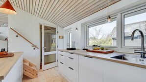 Een moderne keuken met witte kastjes, een houten aanrechtblad, een ingebouwde spoelbak en een raam met uitzicht op buiten.