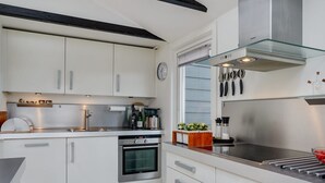 Eine moderne Küche mit weißen Schränken, einem eingebauten Ofen, einer Dunstabzugshaube aus Glas und Edelstahlgeräten.