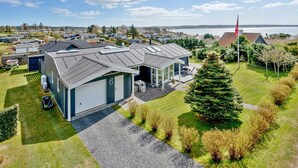 Ein modernes Haus mit Garage, einer überdachten Sitzterrasse und Blick auf das Meer.