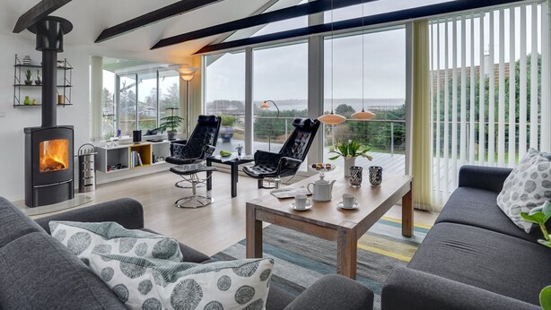 Ein modernes Wohnzimmer mit Kamin, großen Fenstern und einem Balkon mit Blick.