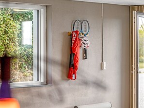 A wall-mounted rack with sports equipment, including tennis rackets and a red sports bag.